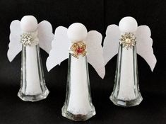 three white angel - shaped vases with gold accents and bows on the top one