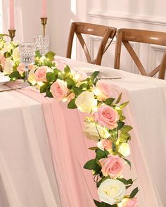 the table is set with pink and white flowers on it, along with two candles