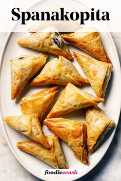 a white plate topped with pastries on top of a marble counter next to the words spanakopita