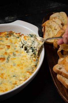 a person dipping some bread into a casserole dish with cheese and spinach