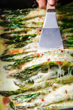 a spatula being used to stir asparagus on top of a baking sheet