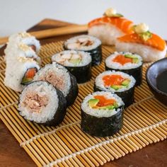 sushi on a bamboo mat with chopsticks and sauce