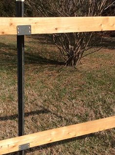 a wooden fence with metal posts in the grass