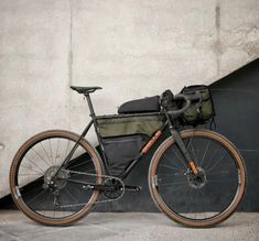 a bike parked next to a wall with a bag on it's back end