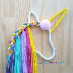 a crocheted pony head with multicolored mane and pom - poms