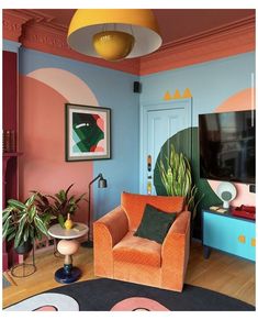 an orange chair sitting in front of a tv on top of a wooden floor next to a blue wall