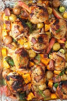 chicken, potatoes and carrots on foil in a baking pan with seasoning sprigs