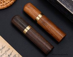 two wooden pens sitting on top of a table next to an old paper and pen