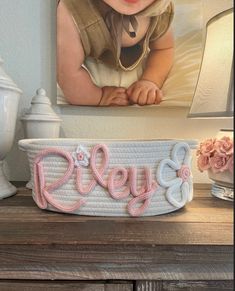 a baby's name cake sitting on top of a table next to a painting