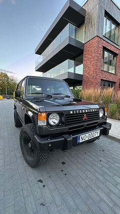 a black suv parked in front of a building on the side of a brick road