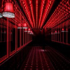 a long hallway with red lights on the ceiling and windows in the center is lit up