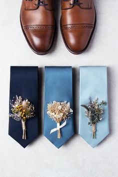 three ties with flowers on them next to a pair of brown shoes and one blue tie