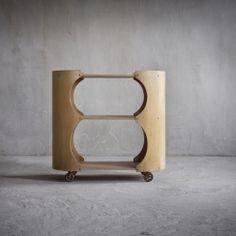 a wooden table with wheels on it in front of a cement wall and concrete floor