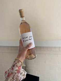 a woman holding up a wine bottle with a note on it that says, i love you by one kiss