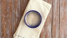 a blue and white bowl sitting on top of a wooden table next to a napkin