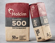 two bags of holcim extra cement sitting side by side on a gray background