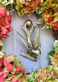 a close up of a wreath with a bird on it and flowers around the wreath