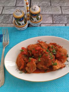 a white plate topped with meat covered in sauce and garnished with parsley