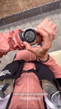 a person taking a photo with their cell phone while wearing an orange jacket and black backpack