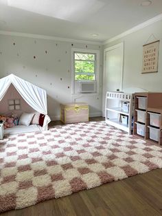 a child's playroom with pink and white carpet, toy storage bins on the floor