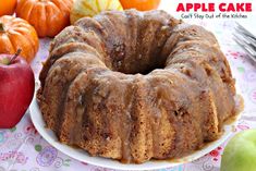 a bundt cake sitting on top of a white plate next to apples and oranges