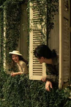 two people are looking out the window of an old building with ivy growing all over it