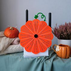 an orange fan sitting on top of a table next to some pumpkins and candles