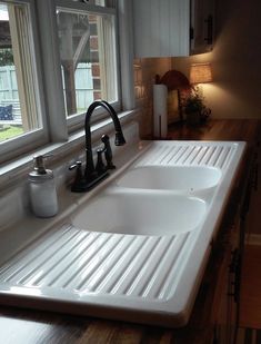 a kitchen sink with two faucets in front of it and an open window