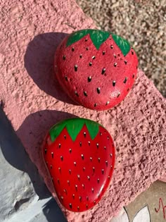 two strawberries are sitting next to each other on a rock with the word hello kitty painted on it