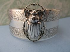 "Myelegantthings presents a gorgeous Scarab Beetles cuff.bracelet. I made these in 1970's for my jewelry line, \"Angelina Verbuni Designs\" 1 inch engraved cuff opens in back The scarab is about 1 inch. 18 K matt gold plating over brass All brass vintage findings. Chic! I have other bangles I've made also with bumble bees, panthers, butterflies and lions and lots of necklaces to match also. Available in silver or gold All USA made" Victorian Brass Silver Bracelets, Vintage Antique Silver Bangle As Gift, Vintage Hallmarked Antique Silver Cuff Bracelet, Nickel-free Vintage Bangle As A Gift, Vintage Antique Silver Cuff Bracelet For Wedding, Silver Brass Cuff Bracelet For Wedding, Antique Hallmarked Cuff Bracelet For Gift, Victorian Hallmarked Cuff Bracelet As A Gift, Vintage Brass Cuff Jewelry