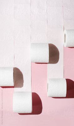 three rolls of toilet paper hanging from a pink wall by luke van der beek for stockstation