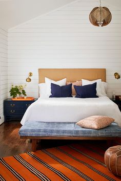 a bedroom with white walls and wood flooring has a large bed in the center