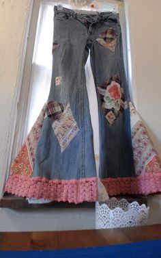 an old pair of jeans with patches and crochet trims hanging from a window sill