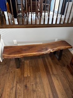 a wooden bench sitting on top of a hard wood floor next to a stair case