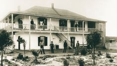 an old black and white photo of people standing in front of a house