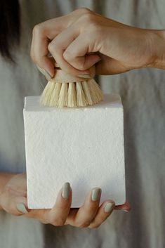 a woman holding a white block with a brush in it