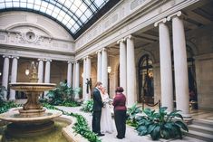 a bride and groom standing in front of a fountain at the end of their wedding ceremony