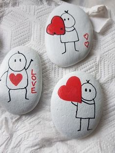 three painted rocks with people holding hearts on them