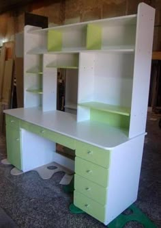 a white desk with green drawers and shelves