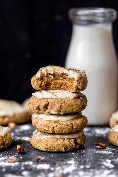 a stack of cookies with frosting and nuts next to a bottle of milk