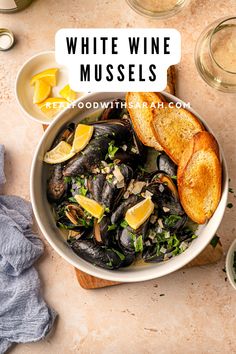 white wine mussels in a bowl with bread and lemon slices on the side