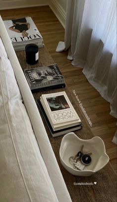 a coffee table with books on it and a bowl sitting next to the couch in front