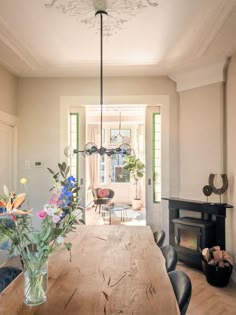 a dining room table with flowers in a vase on top of it next to a fire place