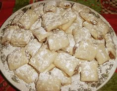 a white plate topped with lots of pastries covered in powdered sugar