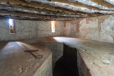 an underground room with stone walls and two small windows on the wall, in which there is a chain hanging from the ceiling