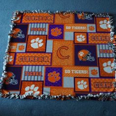 an orange and purple blanket with the word clemson on it, surrounded by paw prints