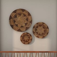 three woven baskets are hanging on the wall above a shelf in a room with white walls