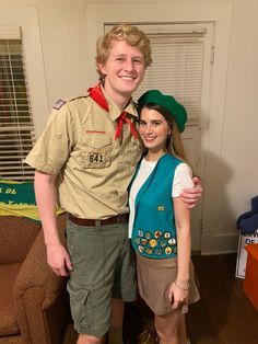 a young man and woman dressed up in scout uniforms standing next to each other on a wooden floor