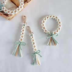 two pieces of beaded jewelry sitting on top of a white cloth covered table next to a basket