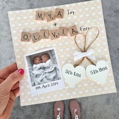 a person holding up a card with two baby pictures on it and hearts attached to them